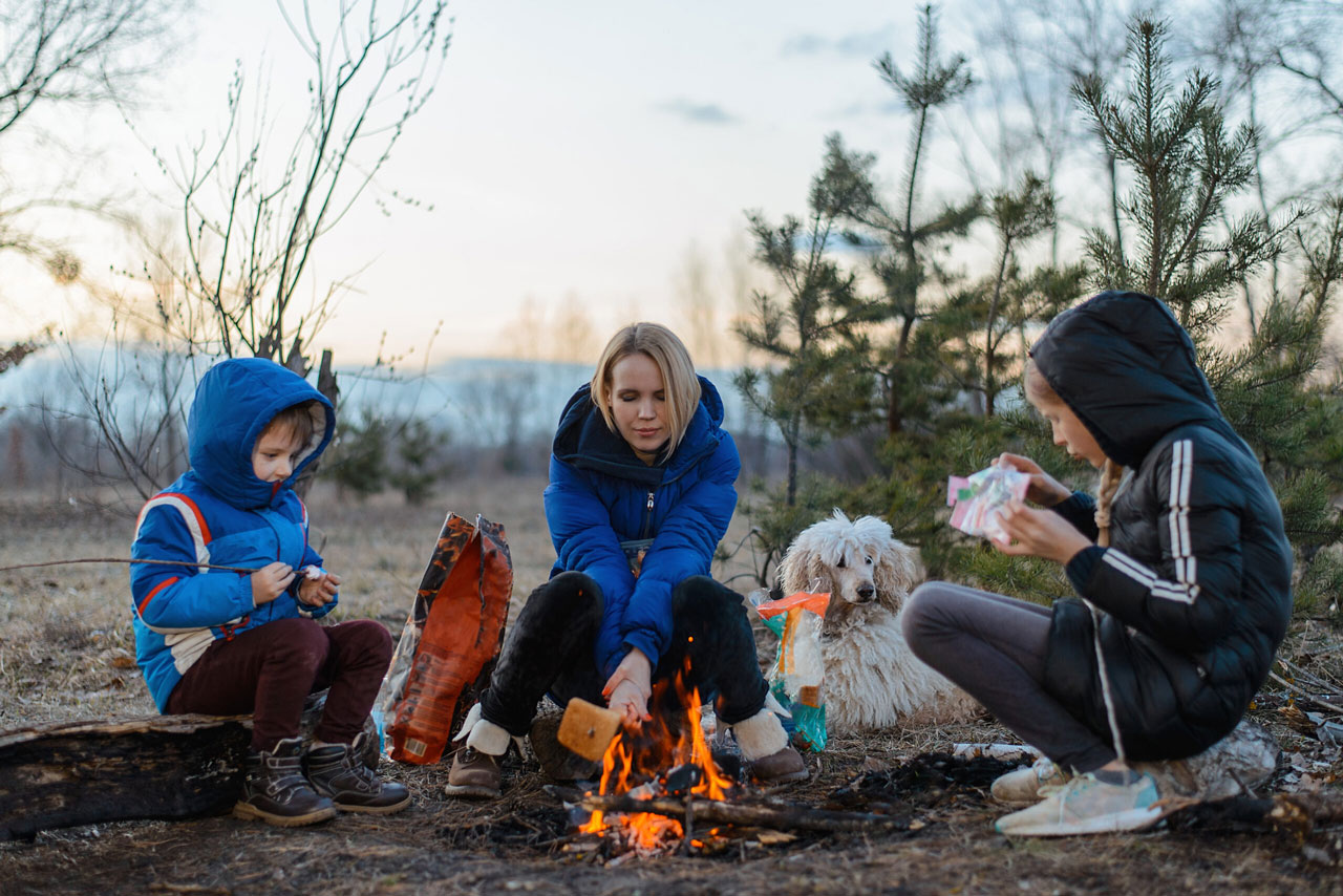 Adult and two young children sitting around fire