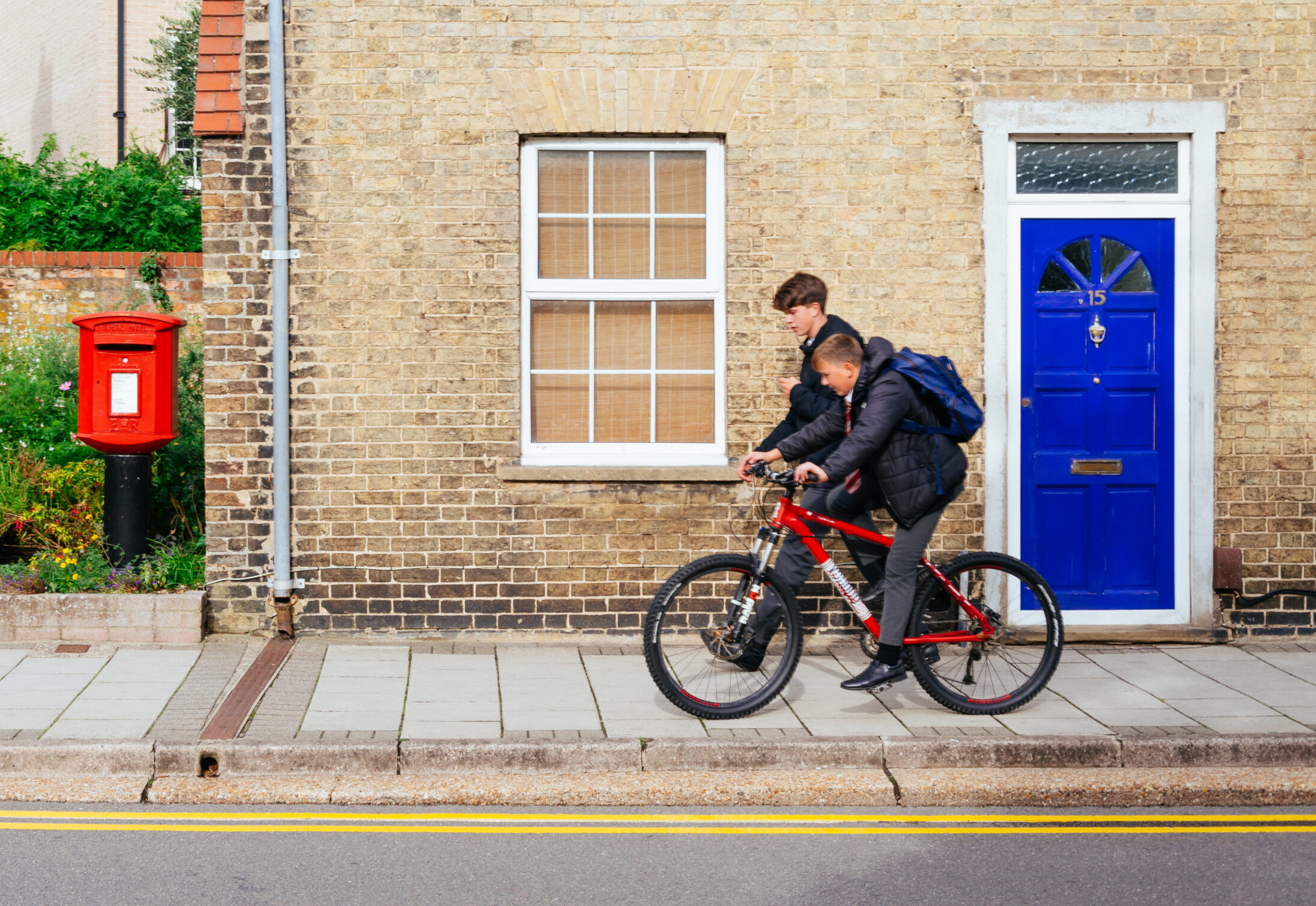 Two boys in school uniform on bicycles
