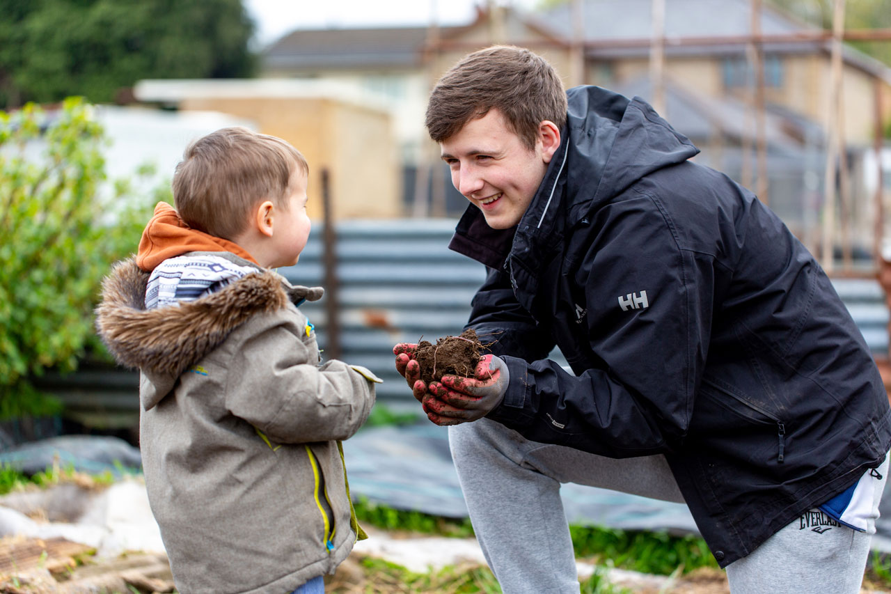 Teenager and young child gardening together in Rhondda Cynon Taf