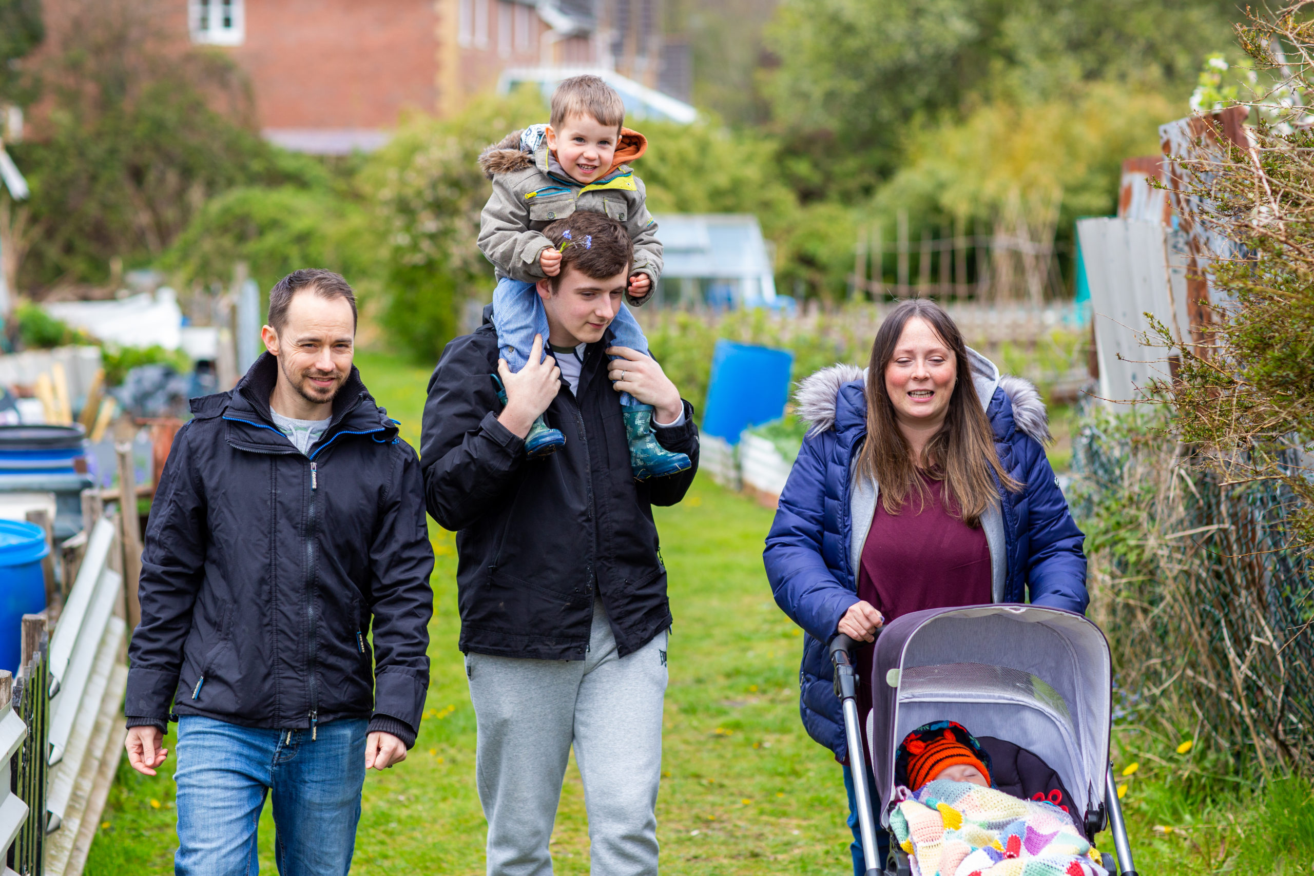 Family with child on shoulders and baby in pushchair