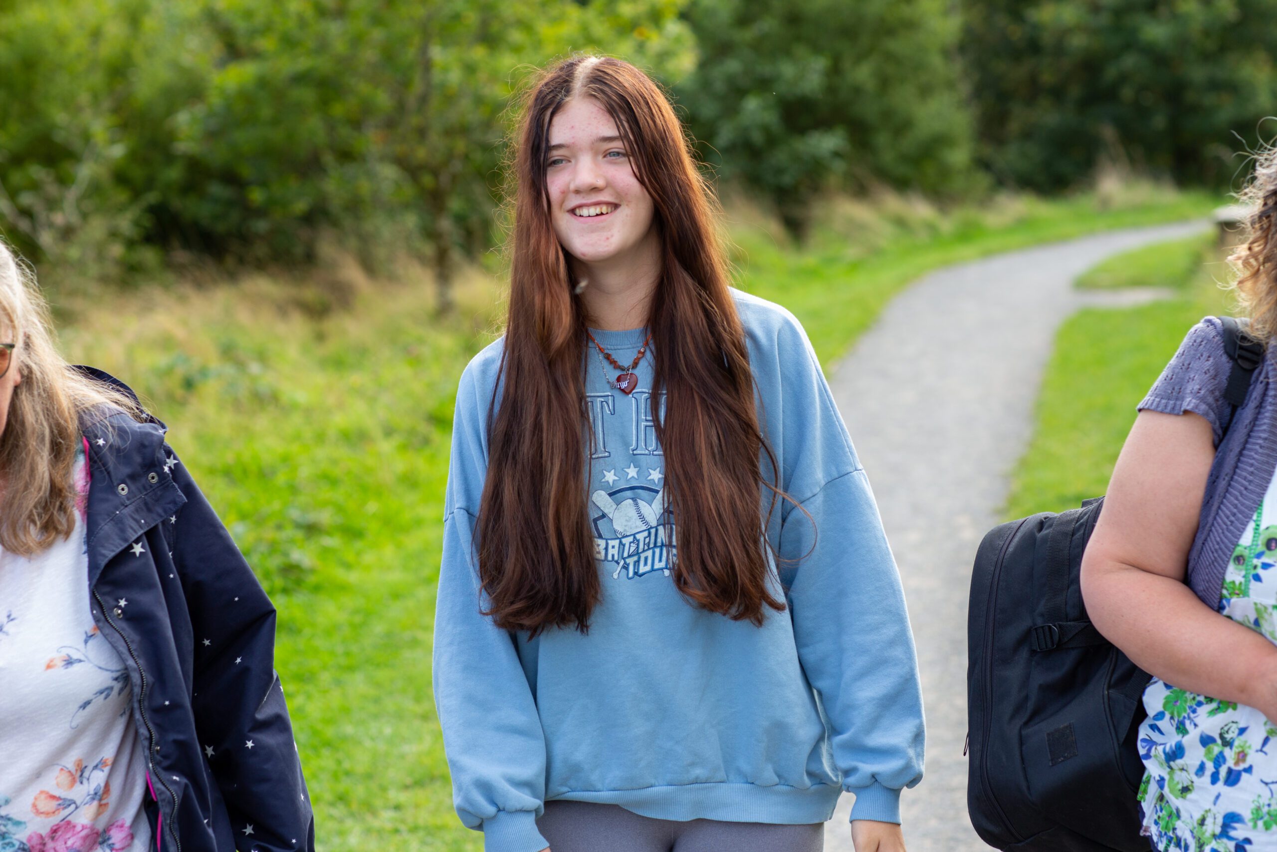 Teenage girl with long hair walking, wearing a light blue jumper