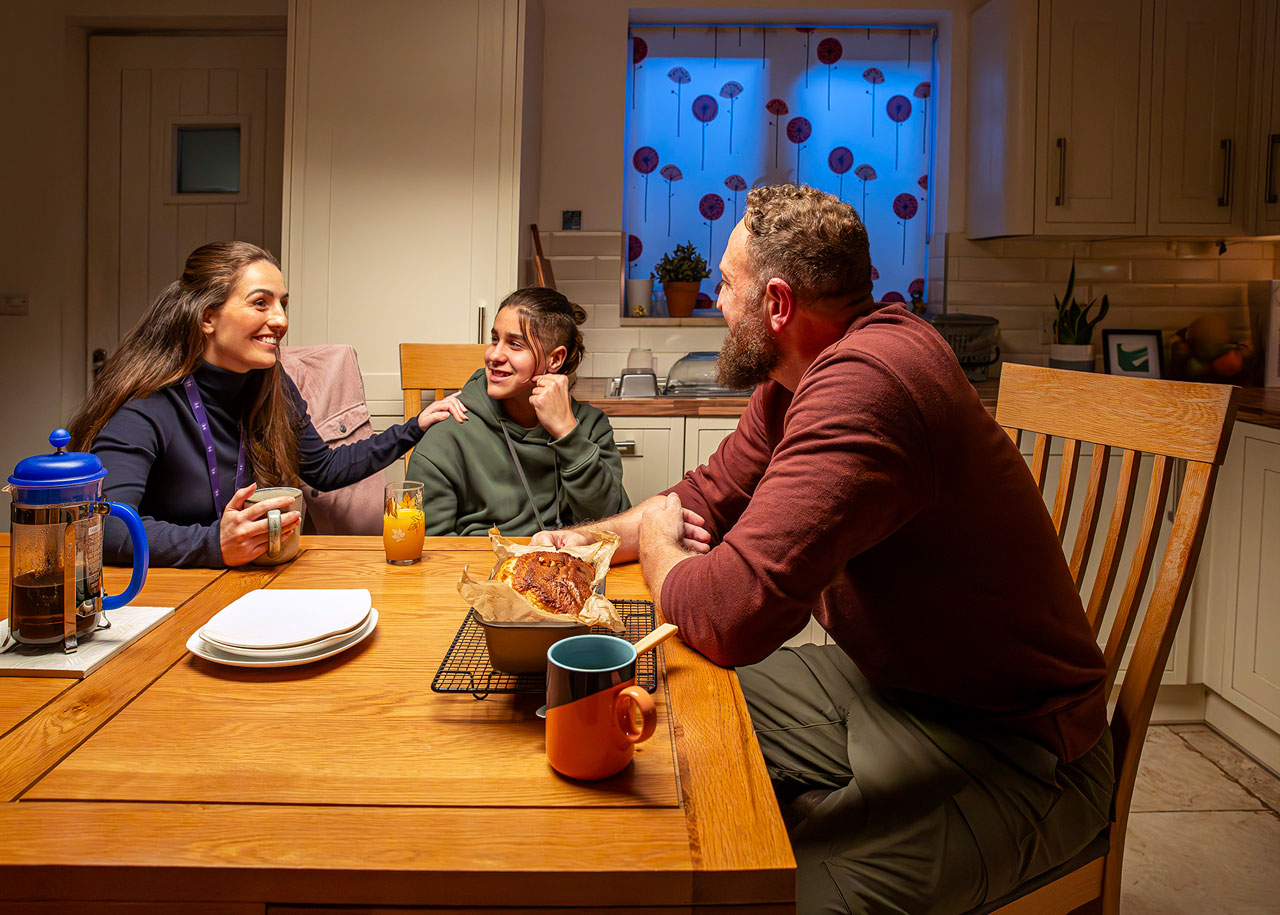 Supervising social worker, child and foster carer sat at a kitchen table